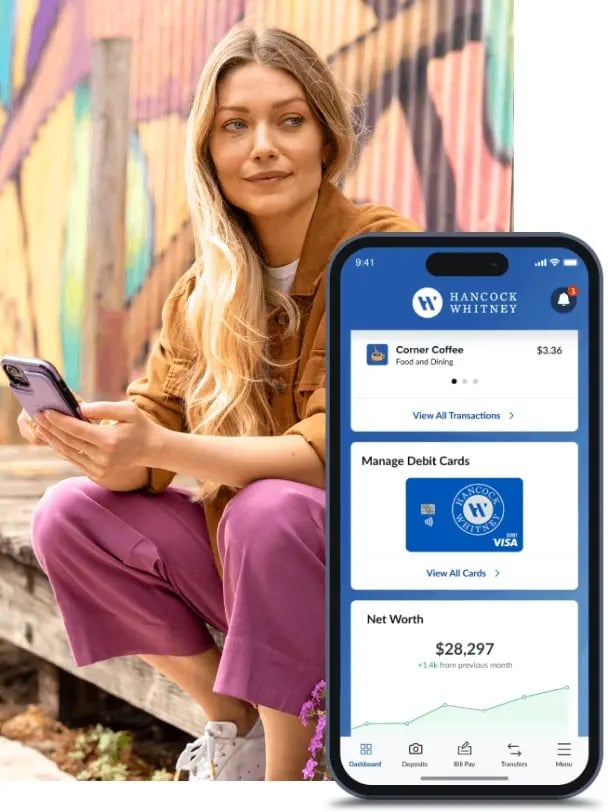 Woman accessing mobile banking on her cell phone, with a cell phone in the foreground showing the Hancock Whitney mobile app