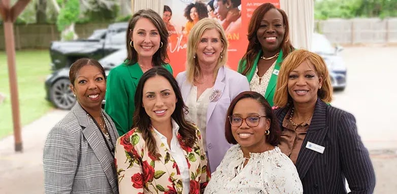 Hancock Whitney employees pose together at an event celebrating women's leadership and empowerment.