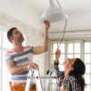 Couple installing a light fixture during a home remodel