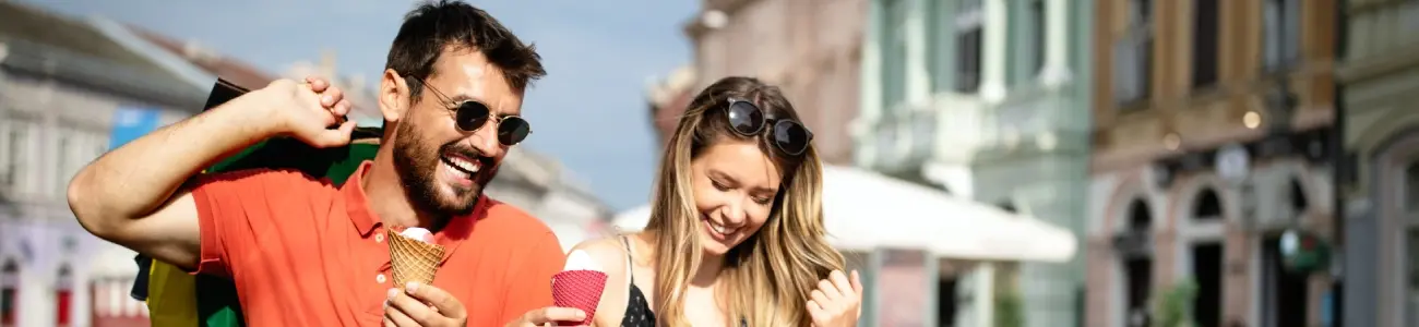 Happy couple eating ice cream while shopping with credit cards
