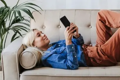 Woman relaxing on a couch while using her phone to access digital banking